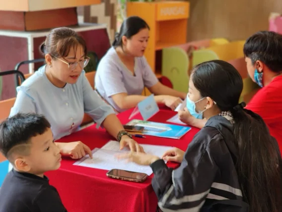 Ảnh chụp một học sinh cùng phụ huynh đang chuẩn bị hồ sơ tuyển sinh lớp 6. Trên bàn có các giấy tờ quan trọng như giấy khai sinh, học bạ, và giấy chứng nhận hoàn thành chương trình tiểu học.