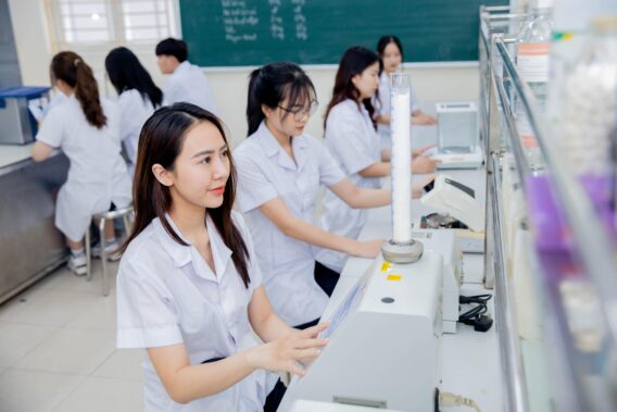 Ảnh ghi lại cảnh sinh viên Trường Đại học Dược Hà Nội đang thực hành trong phòng thí nghiệm dược phẩm, nghiên cứu về các phản ứng hóa học và kiểm tra chất lượng thuốc